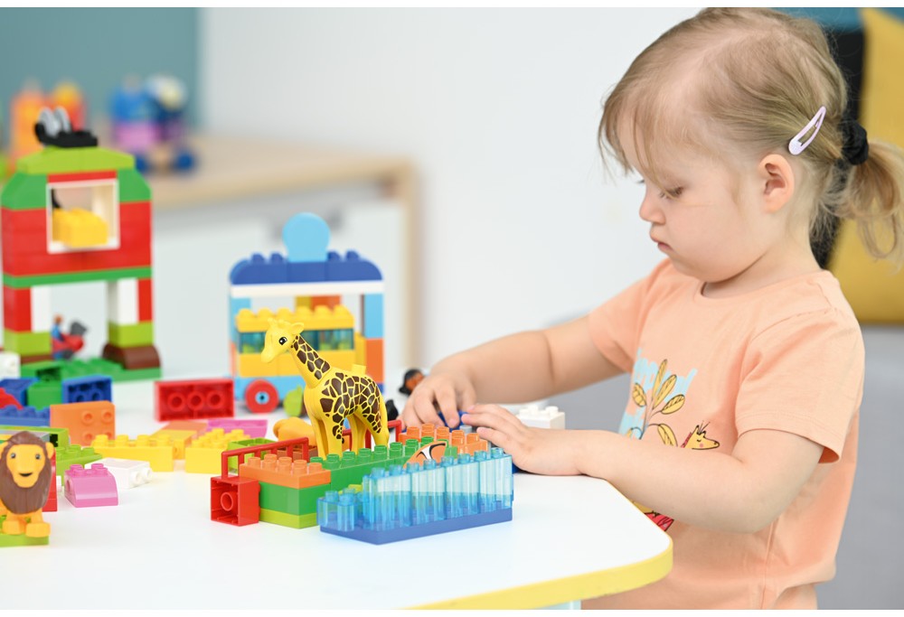 Dievčatko stavia farebný model zo stavebnice LEGO Education SPIKE™ Essential pri stole