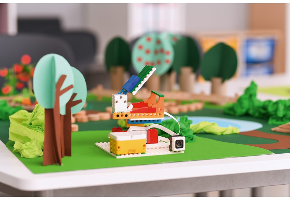 Programovateľný model z LEGO Education SPIKE™ postavený na podložke s papierovou krajinou