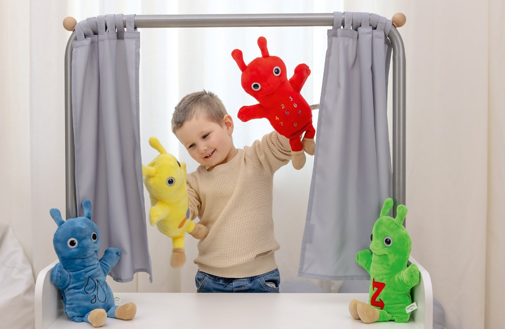 Chlapec sa hrá s farebnými maňuškami za malým divadlom so závesom