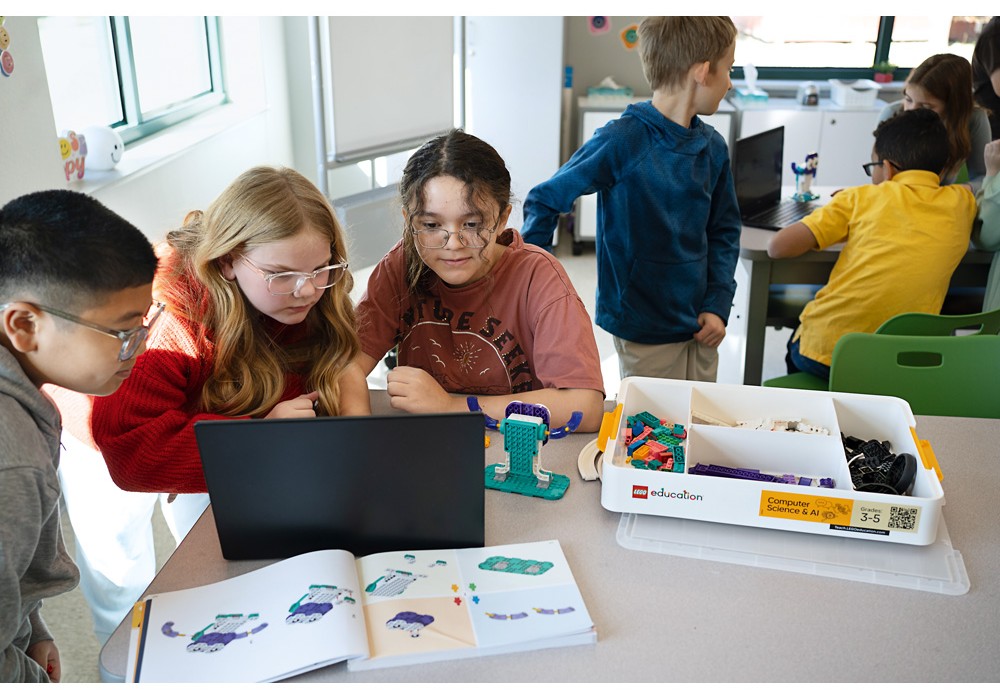 Žiaci pracujú v skupine s notebookom a stavebnicou LEGO® Education Computer Science & AI počas vyučovania.