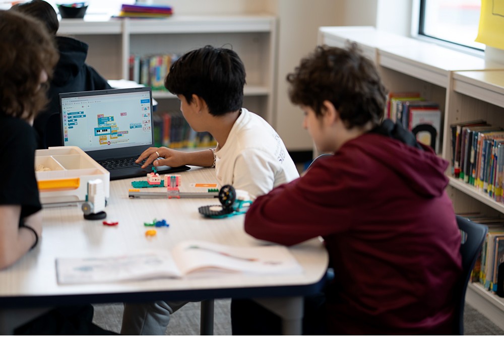Žiaci programujú modely zo stavebnice LEGO® Education na notebooku počas hodiny informatiky a umelej inteligencie.