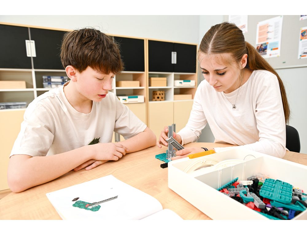 Dvaja žiaci spoločne zostavujú model zo stavebnice LEGO® Education Computer Science & AI podľa návodu.