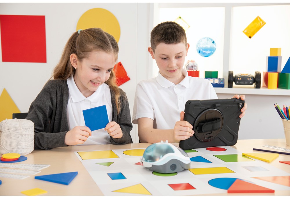Žiaci programujú robota Loti-Bot pomocou tabletu a pracujú s farebnými geometrickými tvarmi.