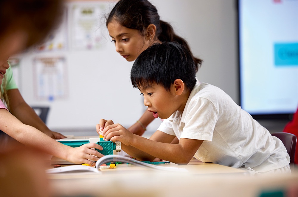 Děti ve třídě staví model z LEGO Education. Skupinová práce podporující spolupráci a kreativní myšlení.