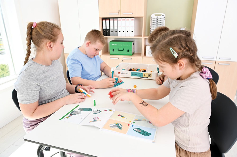 Čtyři děti u stolu sestavují modely podle návodu z LEGO Education Science setu – výuka formou hry a objevování.
